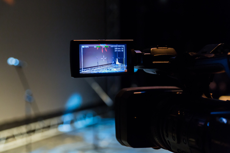 Camcorder with LCD display. Video camera on a tripod before the event. Stage theater or concert hall. Presentation.の写真素材