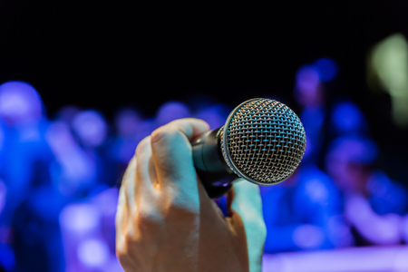 Wireless microphone in hand. Blurred image in the background.の写真素材