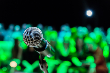 Wireless microphone on the stand. Blurred background. People in the audience. Show on stage in the theater or concert hall.の写真素材