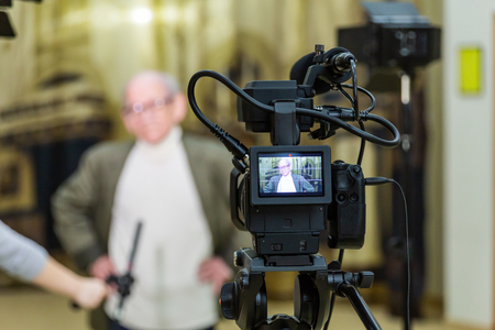 The girl interviews the man. Video shooting in the interior. LCD display on the camcorder.の写真素材