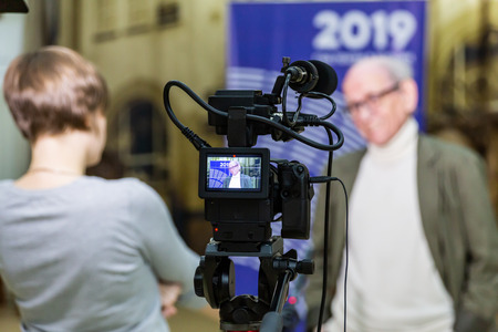 The girl interviews the man. Video shooting in the interior. LCD display on the camcorder.の写真素材