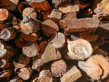 A stack of firewood for the stove in the courtyard of a village house. Wooden texture.の写真素材