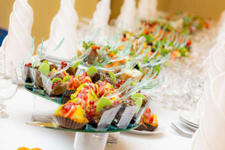 A sumptuously served buffet. Desserts, cakes, snacks on the tables. Restaurant business, catering.の写真素材