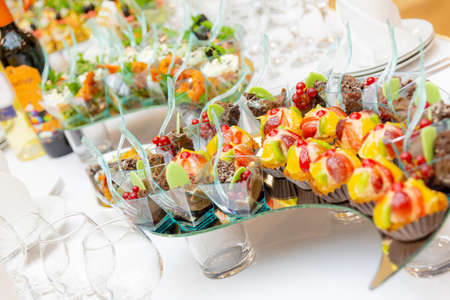 Snacks, delicacies, desserts, bottles of alcoholic beverages on a sumptuously served buffet. Restaurant business, catering.の写真素材