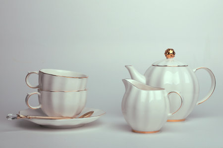 Beautiful white still life with white dishes for tea, coffee, with a golden spoon on a white backgroundの写真素材