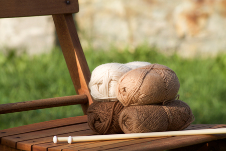 balls of wool in shades of natural tones on a wooden chairの写真素材