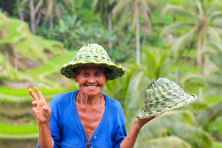 BALI, INDONESIA - September 9, 2013  : happy local woman sell hats in bamboo near rice terracesのeditorial素材
