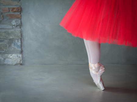 ballet dancer legs with pointe shoes and coral tutu, space for textの写真素材