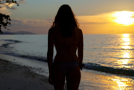 silhouette of young woman back at sunset by the beachの写真素材