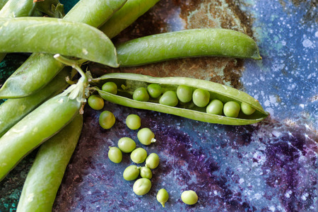 group of fresh green peas close up  on a colored stone backgroundの写真素材