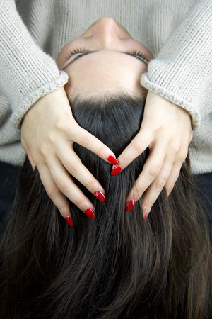 hand of  young woman with red nail polish resting on the headの写真素材