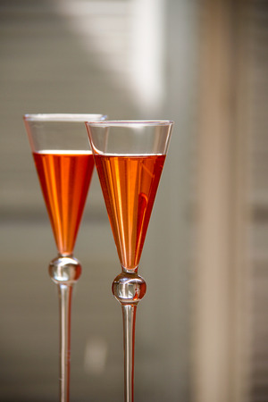 two elegant orange cocktails with multicolored reflections in the glassの写真素材