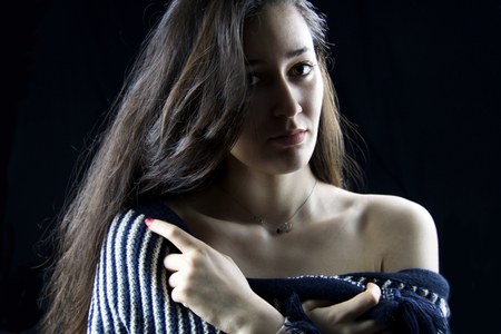 close portrait of young beautiful woman covering her body with wool striped capeの写真素材
