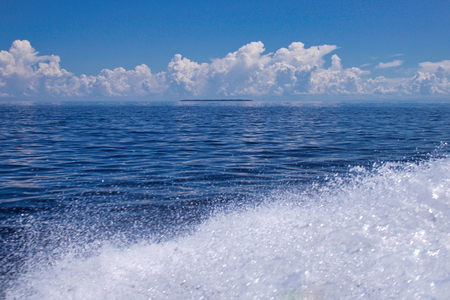 foam of a boat in the celebes sea, kalimantan, borneo, small island on the background in a sunny dayの写真素材