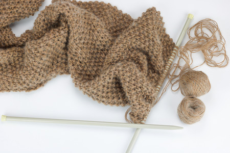 close up of scarf knitted work and large needles, white background