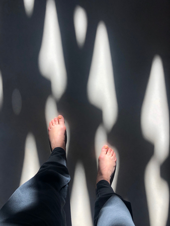 female human feet view from above between light and shadow