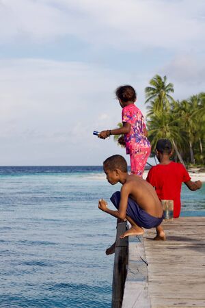 WEST PAPUA, RAJA AMPAT - August 28, 2017 : unidentified asian indigenous children fishing with fishing wire on a  wooden pier of  local village, Raja ampat archipelagoのeditorial素材