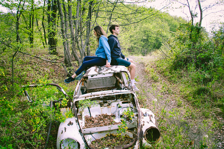 couple of friends sitting on a roof of a white  scrap machine abandoned in the natureの写真素材