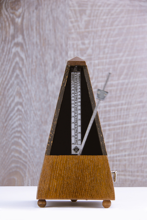 vintage metronome in brown wood in motion on grey wooden backgroundの写真素材