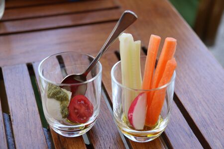 close up of two small glasses with appetizer finger food on wooden table