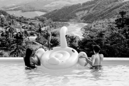 boy and girl with inflatable flamingo in a pool looking landscape, black and whiteの写真素材