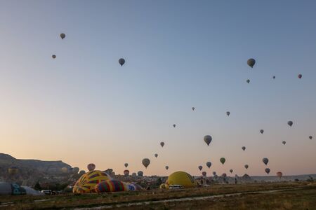 Goreme, Turkey - August 31, 2019: large group of multicolored  hot air balloons take flight from cappadocia fields at downのeditorial素材