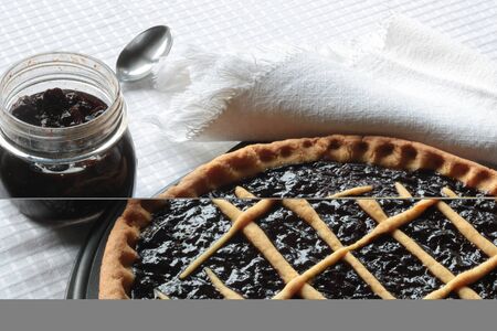 plum jam tart and plum jar on white tablecloth, copy spaceの写真素材