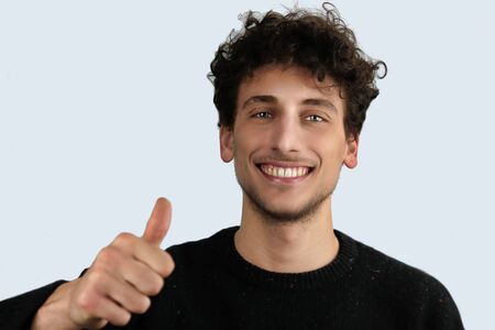 portrait of cheerful teenager smiling  with thumbs up on white backgroundの写真素材