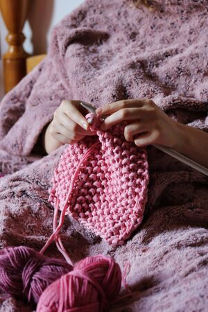 female hands of young woman knitting pink cotton yarn
