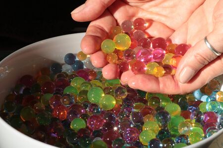 group of brighting multicolored hydrogel balls in female hands