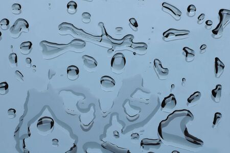 group of water drops on a glass surface, light blue background