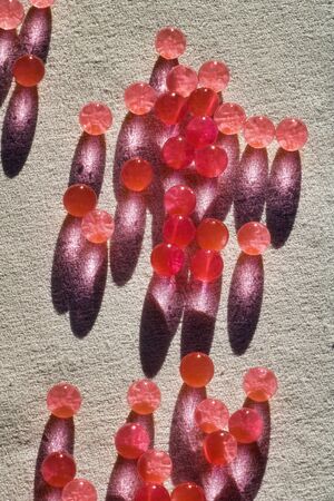 group of red hydrogel balls and their shadows on grey fabric