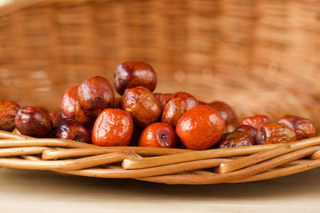 orange jujubes fruits in a wicker basket on a wooden tableの写真素材