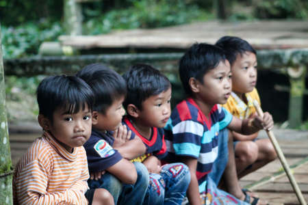 Rantepao, Sulawesi - August 23, 2014: group of five unknown indonesian children sitting close together participating in a funeral ceremonyのeditorial素材