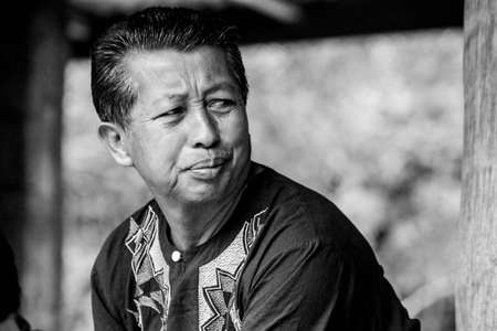 Rantepao, Sulawesi - August 23, 2014: portrait of unknown indonesian man in dark decorated shirt sitting and looking away, lack and whiteのeditorial素材