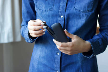 woman taking electronic cigarette from charger, copy spaceの写真素材