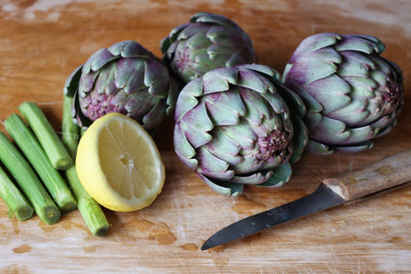 preparation of purple artichokes just washed on wooden cutting boardの写真素材