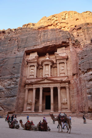 Petra, Jordan - August 31, 2022: group of camels and tourists in front of the treasury magnificent facade one of the most elaborate temples in Petra archaeological siteのeditorial素材