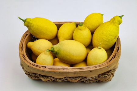 group of fresh lemons just collected in wicker basket, isolated on white