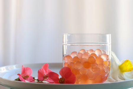 texture of bubble tea obtained by inverse spherification in a glass, white curtain in backgroundの写真素材