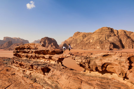 two tourists walking on small stone bridge in wadi rum desert, Jordanの写真素材