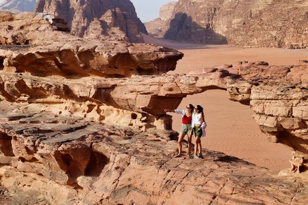 close view of two tourists on rocks visiting wadi rum desert, jordanの写真素材