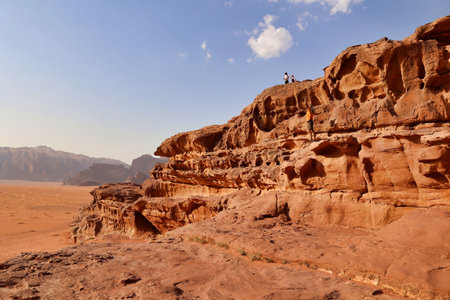 touists on rock formations visiting wadi rum desert, jordanの写真素材