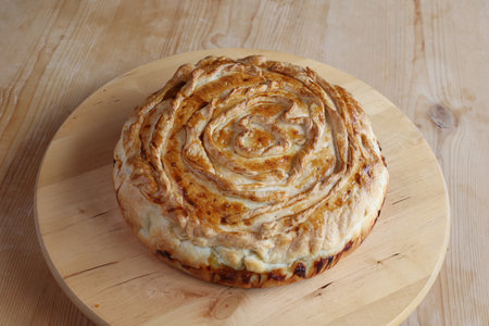 italian Pasqualina savory cake on wooden plate, wooden background, copy space