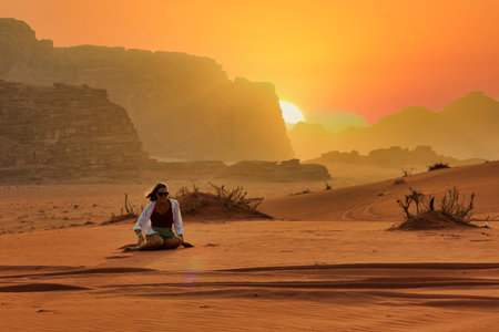 young woman playing in the sand of wadi rum desert at sunset, jordanの写真素材