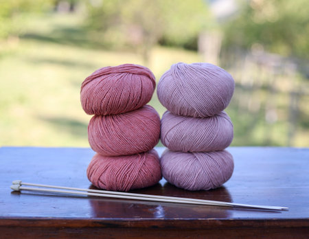 group of merino wool balls of yarn in two shades of pink on wooden tableの写真素材