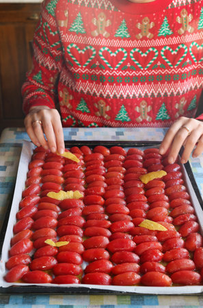 woman preparing peeled confit tomatoes in a baking sheetの写真素材