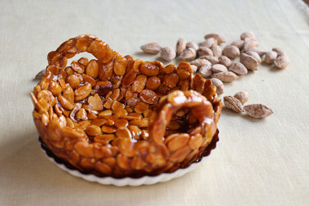 close view of almonds brittle as small basket on linen tableclothの写真素材