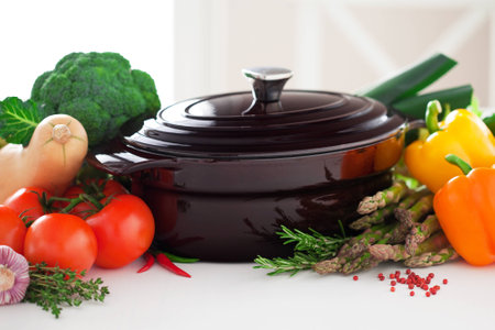 Cast iron pot and fresh vegetables on the table, selective focusの写真素材