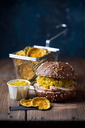 Gluten free Burger with sliced roast meat and cucumber relish, zucchini chips, selective focusの写真素材